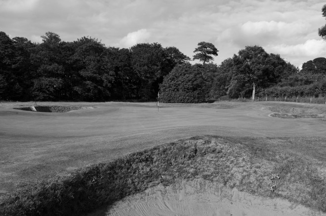 The view of the undulating 10th green from front right, over one of six bunkers that encircle the putting surface.
